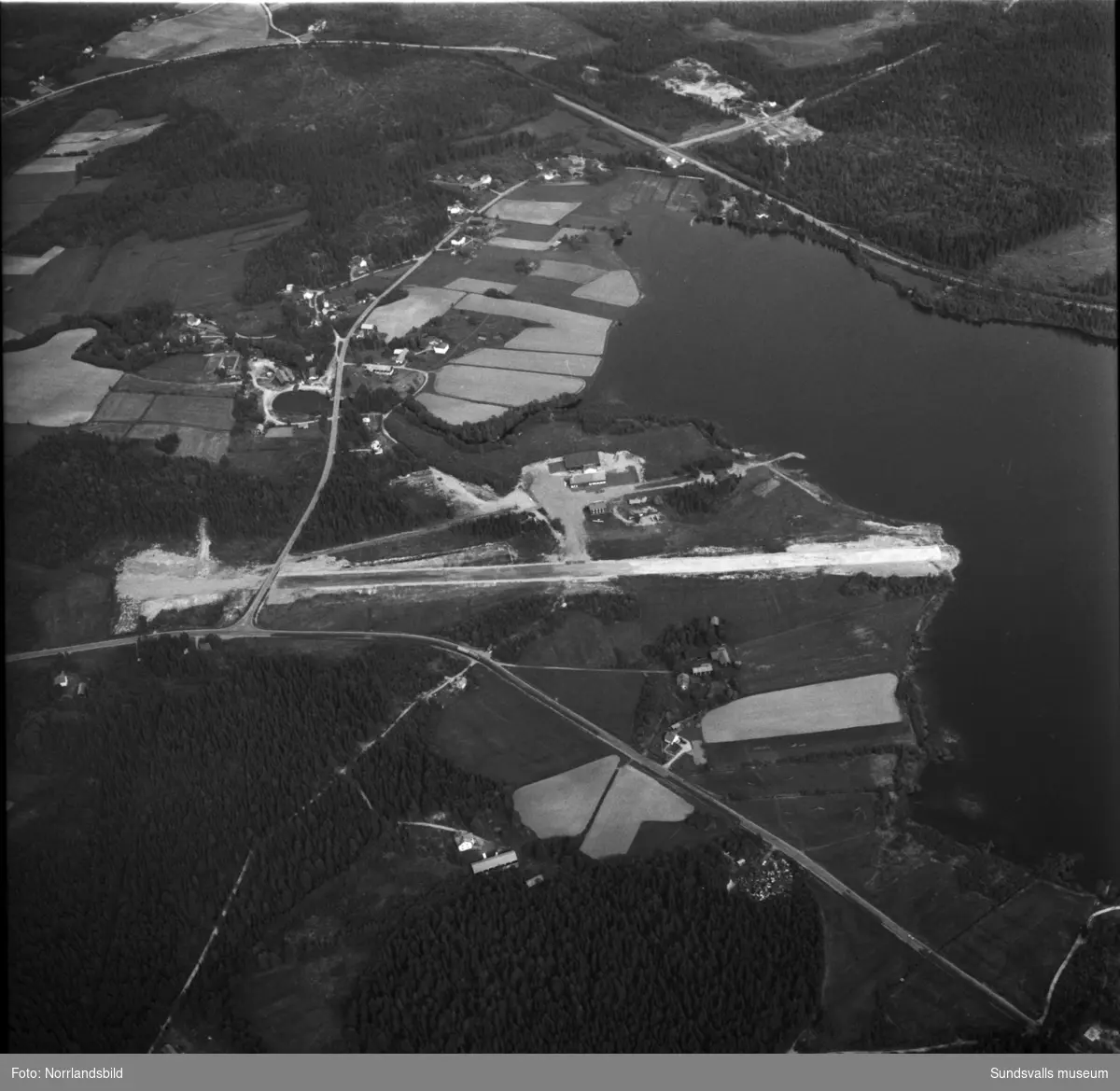 Flygfoton över det lilla flygfältet i Maj, Ovansjö, invid Bölesjön samt omgivande bebyggelse.