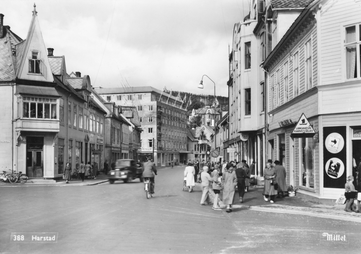 Nedre del av Strandgata, med Helga Lind til venstre, Hoelgården til høyre og Grand i bakgrunnen. I forgrunnen fotgjengere, syklist og lastebil.