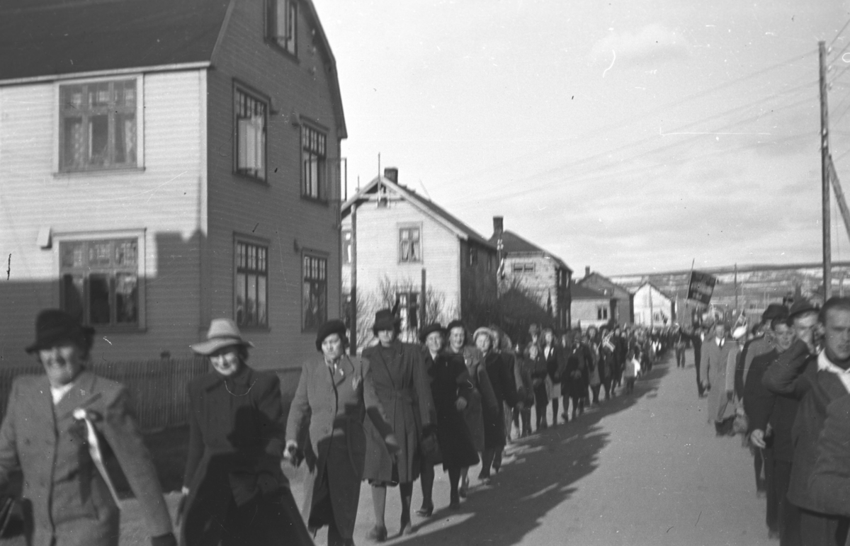 Et tog går gjennom ytrebyen i Vadsø. Det er så lite norske flagg i toget at det er tvilsomt at det er 17. mai-tog. Erling Stålsetts hus ses til venstre på bildet og nederst til venstre ses fru Skogsholm.