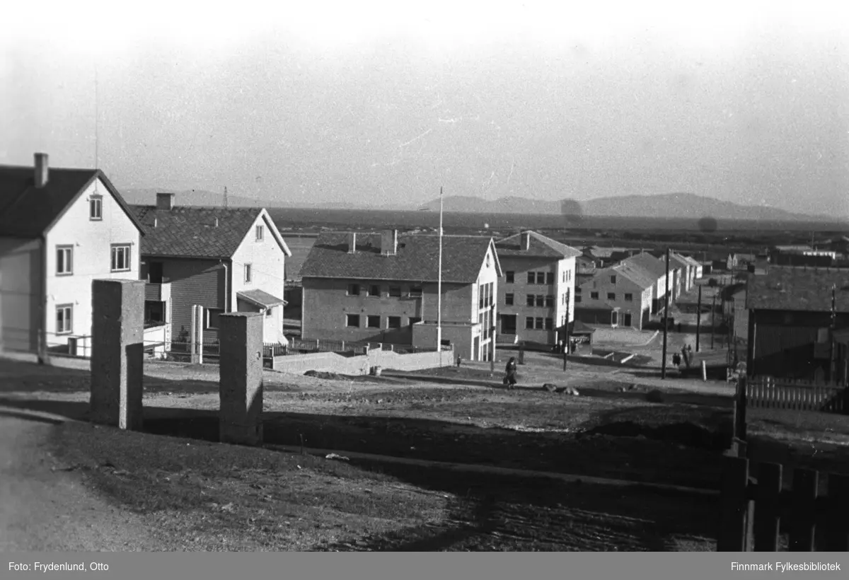 Gjenreiste sentrumsbygninger i Vadsø fotografert nedover Tollbugata mot torget. Hus nr. 3 og 4 på venstre side av veien er Vadsø sparebank og Vadsø rådhus, sistnevnte med en liten paviljong utenfor