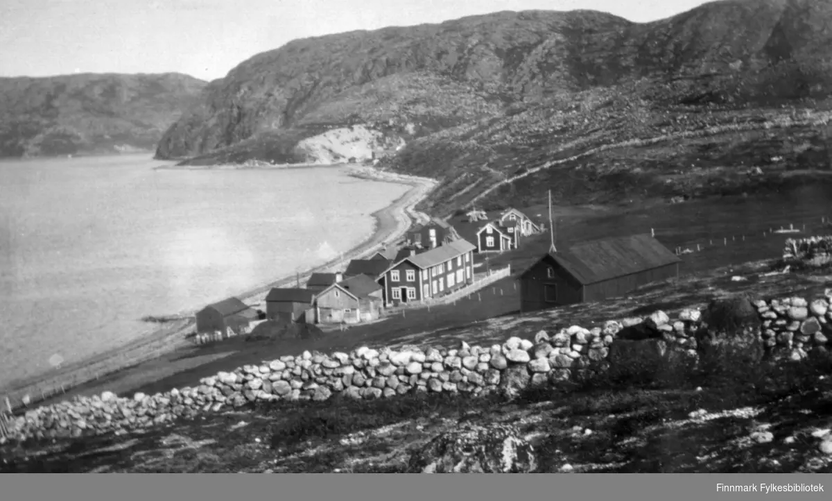 Oversiktsbilde over familien Gunnaris hus og kulturlandskapet rundt Bugøyfjord. Det øverste huset er høysjå. Ellers ser vi fra venstre ved vannet sjøbod, ovenfor den fjøs med stall, sauefjøs og hønsehus. I midten ser vi hovedhuset og nest lengst til høgre Rauhala. Ca.1915-1920.
