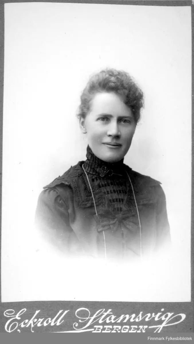 Portrett av en dame iført en mørk bluse med høy hals.