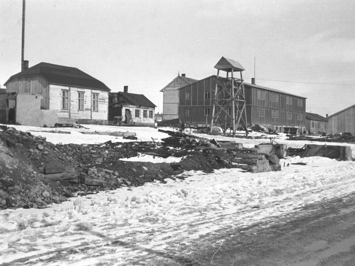 Fra gjenreisningstiden i midtbyen i Vadsø. Klokketårnet ses midt på bildet og bak det ses skolebrakka. Bedehuset med valmet tak ses til venstre på bildet.