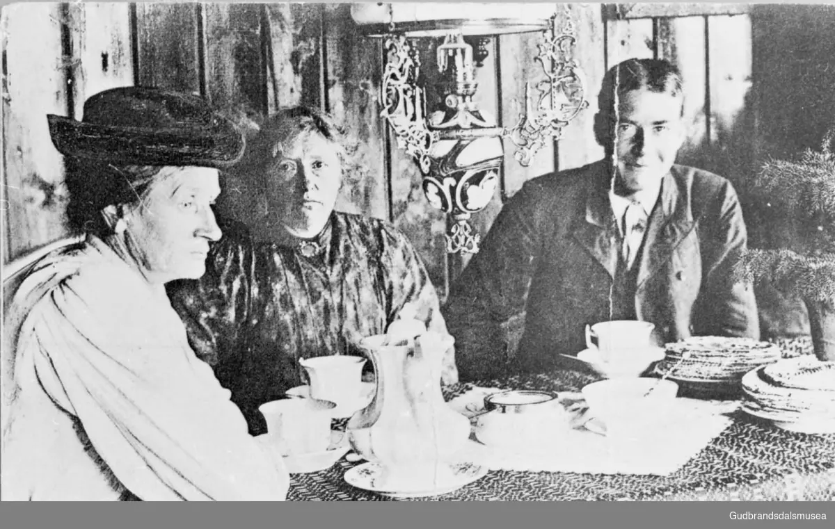 Tre personer sitter ved bordet, servering av skrivarbrød og rømmebrød til kaffen, interiør fra Flittie.