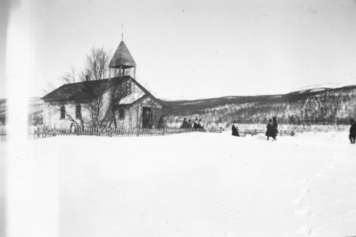 Folk på vei til kirken, eller kapellet i Polmak. Det er vinter, og snøen ligger på bakken