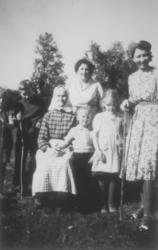 Bestemor Elen Marie Arnesen som sitter omgitt barn, barnebar