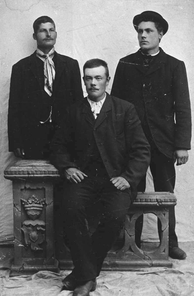 Tre menn fotografert av Einan. Alle ukjente. To av dem står mens en sitter på en gjerde-illustrasjon.