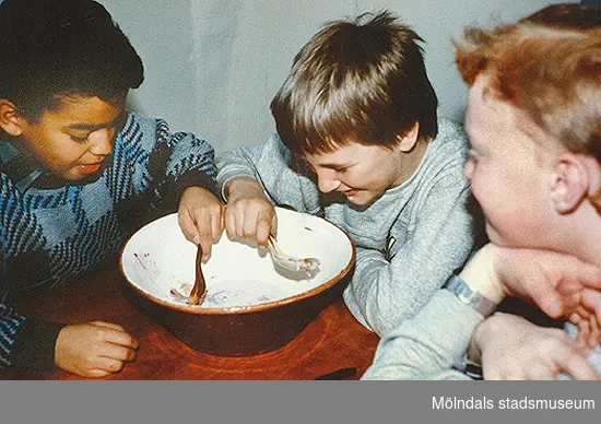 Barn som äter korngröt ur en gemensam skål. Pedagogik på Mölndals museum, okänt årtal.