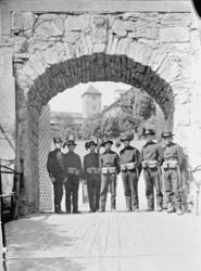 Sju unge menn, soldater i uniform med tilbehør, oppstilt i e