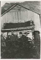 Tre personer i samtale foran et eldre hus. Børre Berli til h