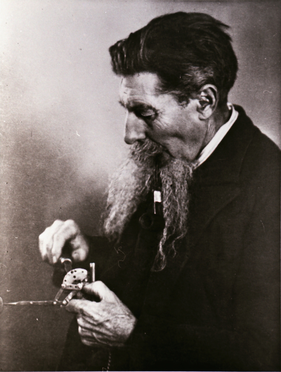 Portrett av en mann som finstiller et instrument/ apparat.