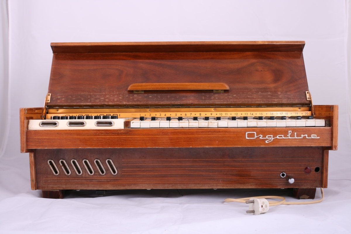 Elektrisk akkordorgel av firmaet Quagliardi med 34 tangenter og 48 akkordtaster. Kasse i tre. Lokket fungerer også som notestativ