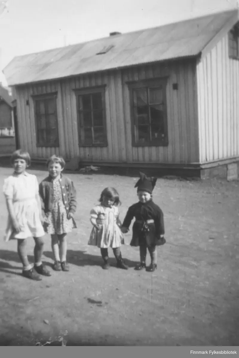 Fire barn poserer for fotografen foran et bygg. Personer og sted er ukjent.