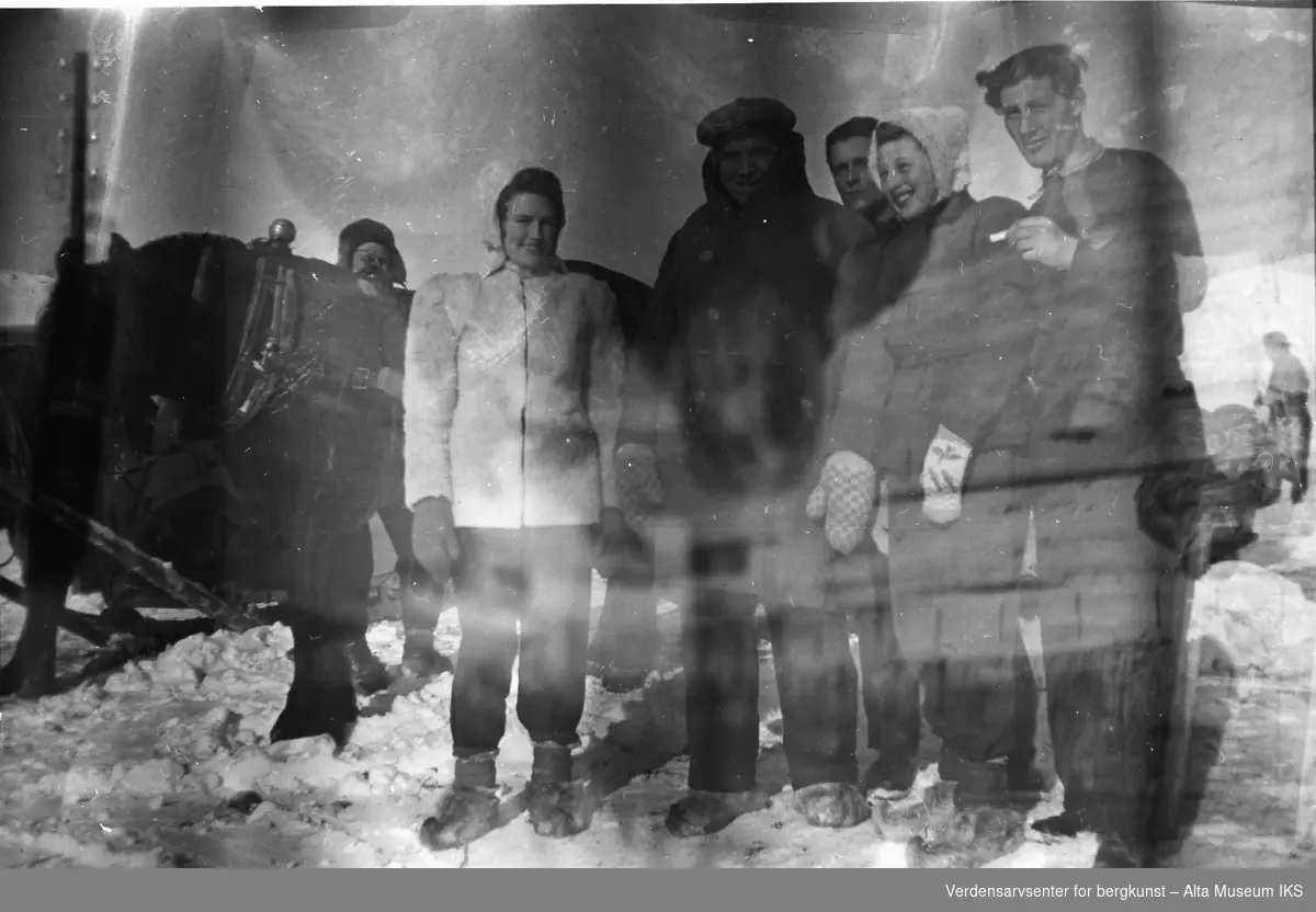 Fem venner står foran hesten Jacob og smiler til kameraet. En mann står på andre siden av hesten. Erna Jøraholmen er iført en hvit vinterjakke.