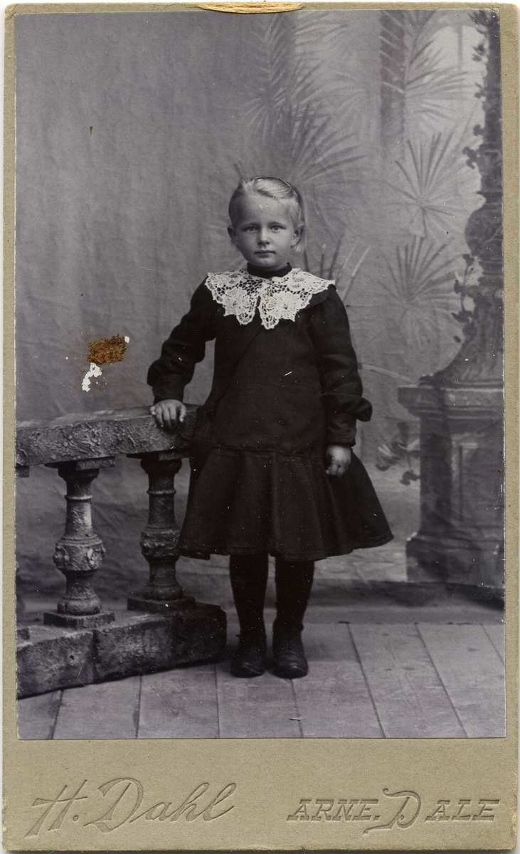 En liten jente står ved siden av et gelender.