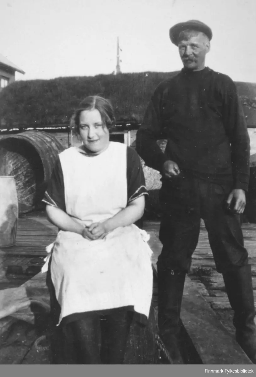 En kvinne og en mann fotografert på en kai, muligens i Hamningberg, eller i Kiberg. Kvinnen er Gudrun Bauna og mannen heter muligens Hagala, fornavn ukjent.