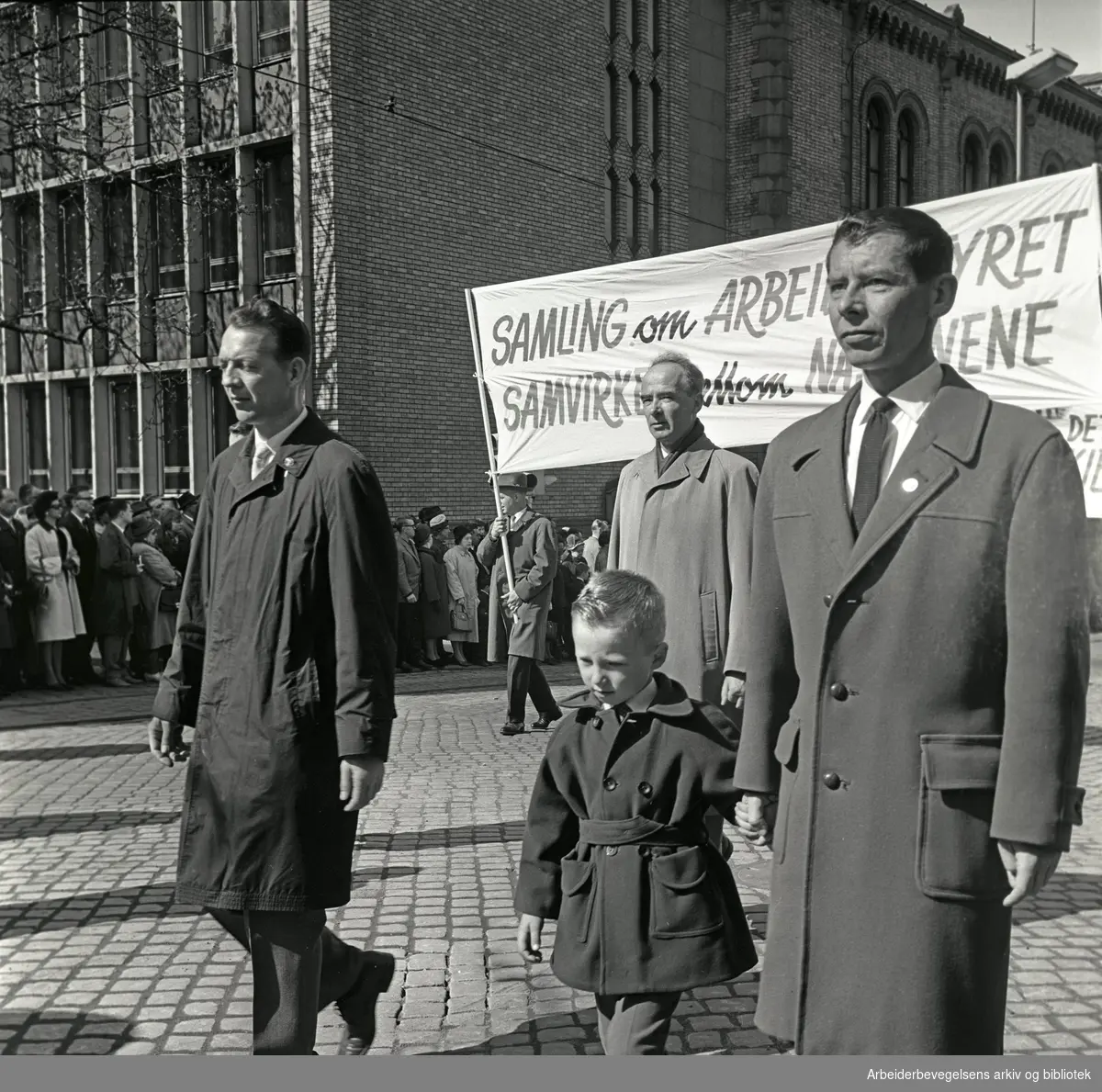 1. mai 1964 i Oslo.Demonstrasjonstoget i Karl Johans gate.Parole: Samling om arbeiderstyret.Samvirke mellom nasjonene.I midten bak: Trygve Bratteli..