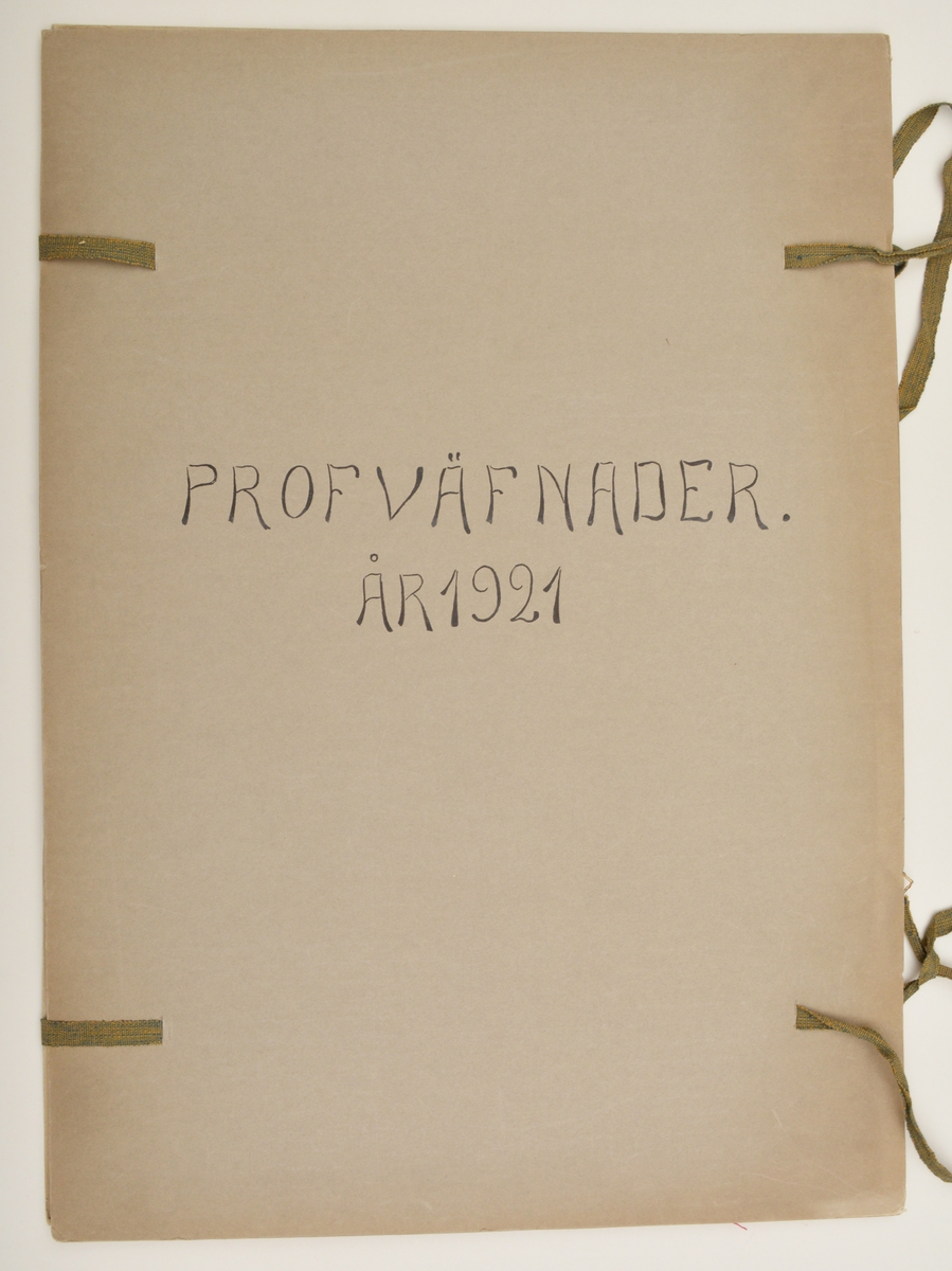 Stor pappersmapp med lösa blad med påklistrade tygprover. Pärmarna är av en annan papperskvalité än papperna innuti. Pärmarna hålls ihop med ett par långa, handvävda band.
Text på framsidan; "Väfprofer År 1921".
