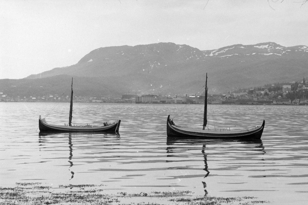 To små nordlandsbåter, med byen i bakgrunnen.