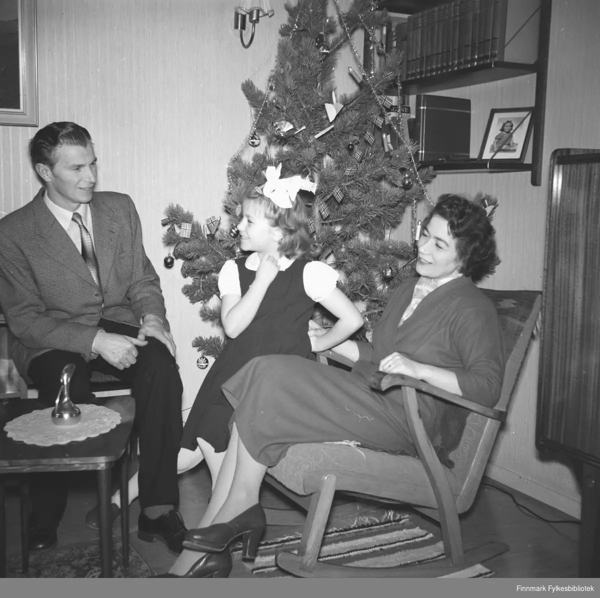 Familieportrett av Eino, Turid Lillian og Jenny Drannem ved juletre, tatt i jultiden i stua