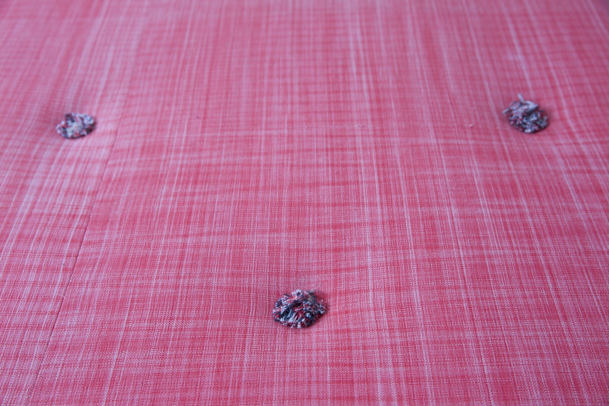 Polstret madrass med fjær på trebunn med bord. Smårutete trekk i forskjellige nyanser av rødt/rosa og hvitt. Hanker laget av samme stoff på kortsidene.