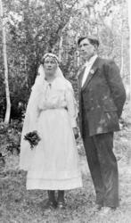 Portrett, brudepar utendørs, trær i bakgrunnen.