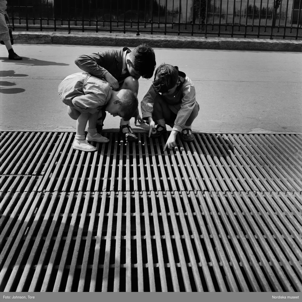 Paris. Tre pojkar leker på ett ventilationsgaller.
