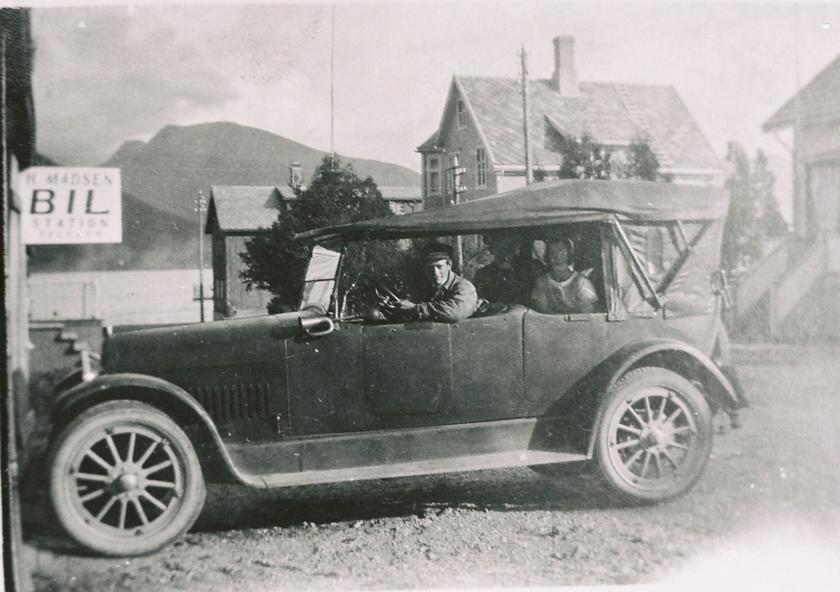 H. Madsen Bil Station, Sortland. Bilen er en Nash ca. 1923/24-modell. Bilstasjonen lå mellom Johnsengården og Arntzengården, det var den første drosjesentralen på Sortland. Ingvald Madsen ved rattet. Det var en kald fornøyelse å site på en 7 seter cabriolet.