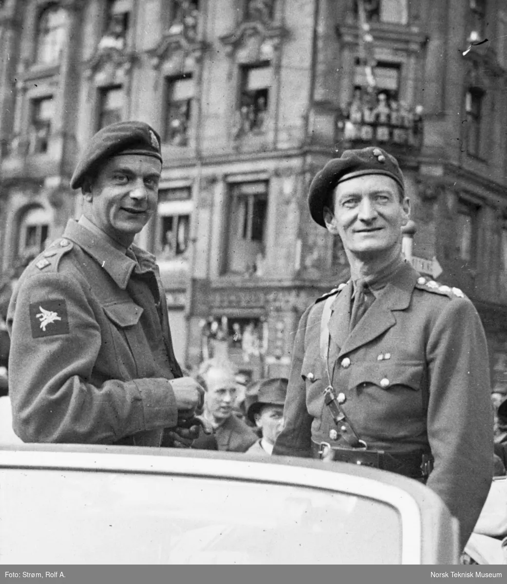 To menn i militære uniformer på en bil, foran folkemengde, Oslo mai 1945,