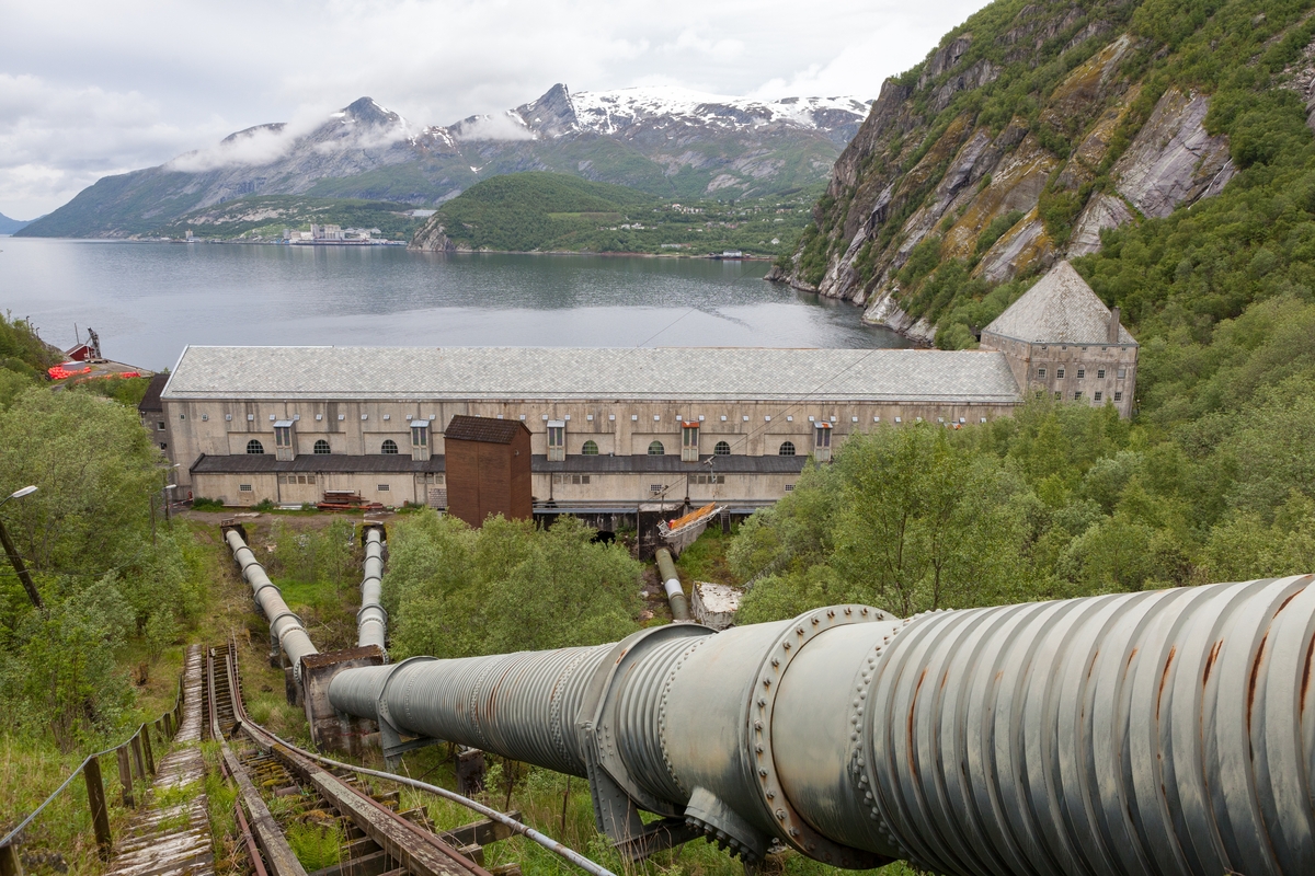 Glomfjord kraftverk med røyrgate og rester av trallebane, i bakgrunnen ser vi industristaden Glomfjord.