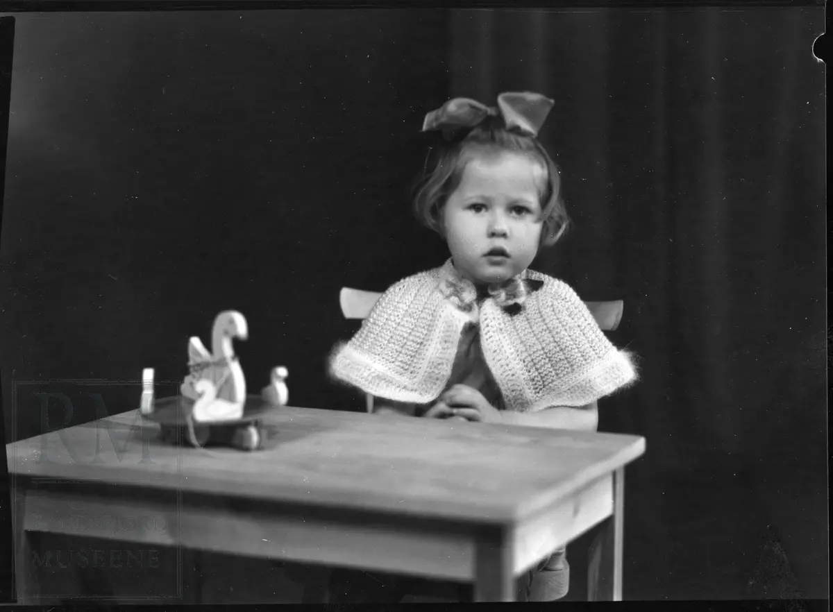 Portrett av jente ved et bord. Gerd Anni Skjerstein