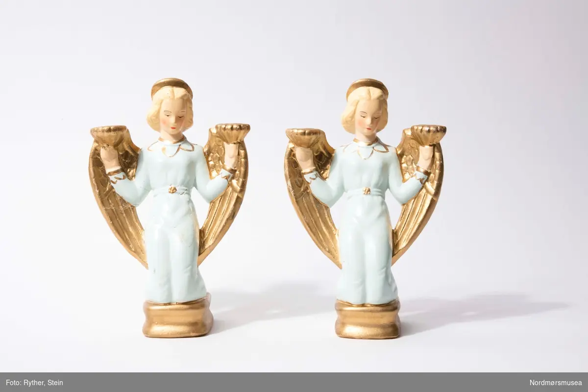 To lysestaker med plass til to tynne stearinlys, formet som engler. Englene har lyst hår og er kledd i lyseblå kjoler med gulldekor. Englene kneler på en sokkel.