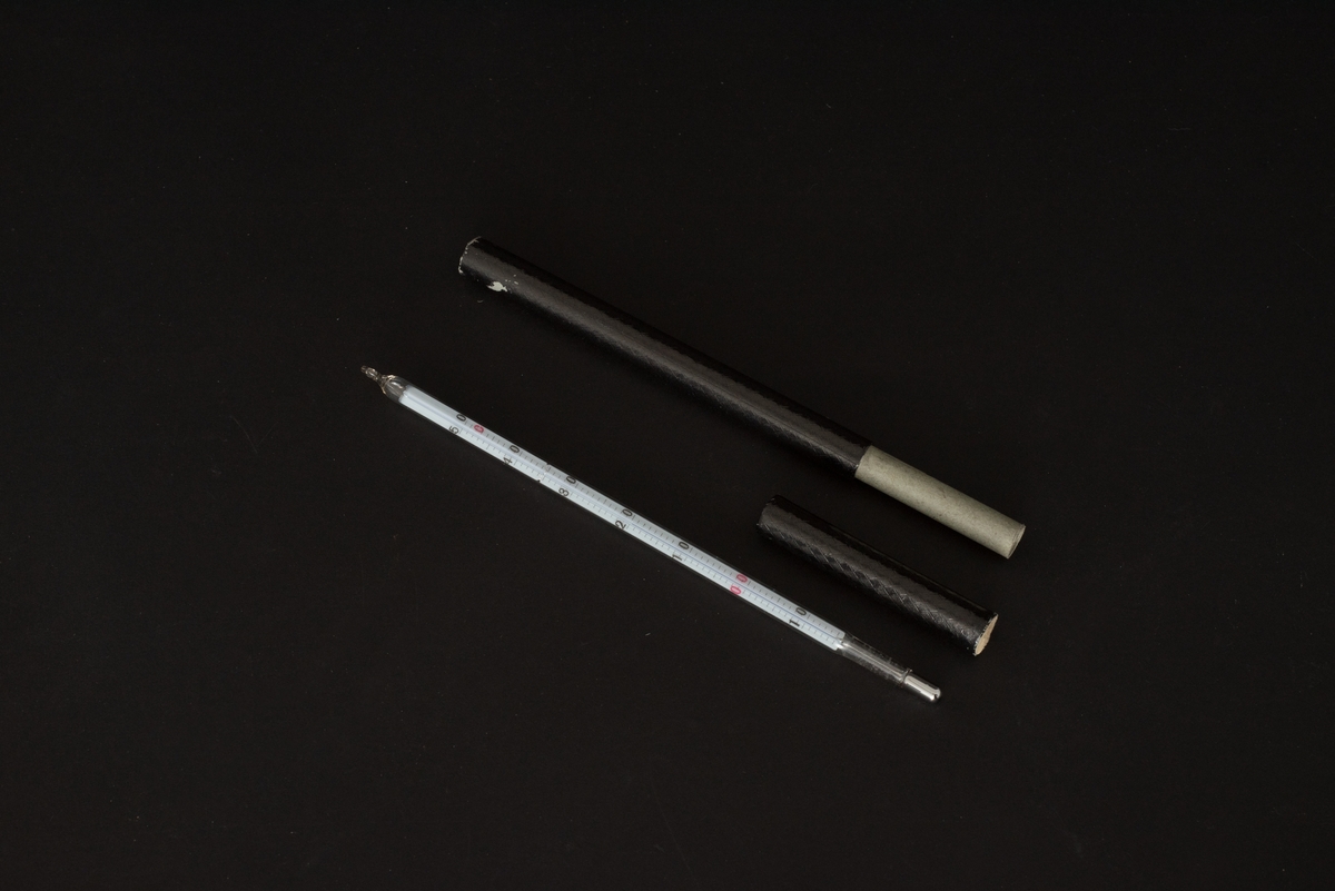 Termometer, långsmal (kvicksilver). Rund glascylinder. Förvaras i svart pappcylinder.