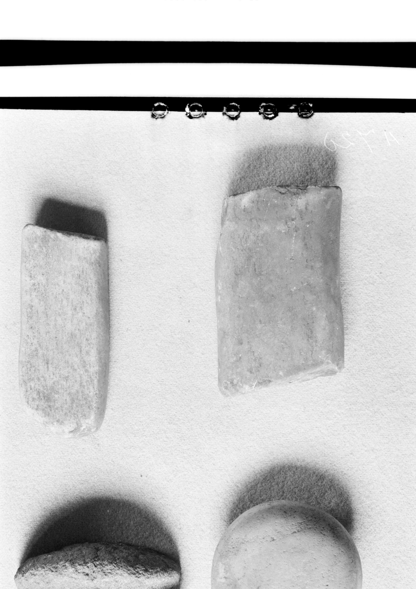 "4900 g. Flat sten av kvartsit, en naturdannet sten, 7,4 cm. l., 6,9 cm. b., tykkelse 3,1 cm. Viser i begge ender spor efter å ha vært brukt til knusning (avb. Gamle gårdsanlegg 1933,  pl. 2, fig. 2)."
Slagstein av gråhvit kvartsitt, flatoval i formen, med knusespor i begge poler. Stl: 76 mm, stbr: 70 mm, stt: 32 mm.
