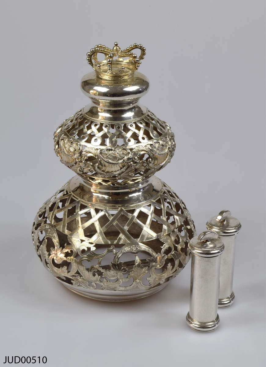 Torahkrona, tillverkad av silver, med löstagbara stavar. Genombruten dekor, och dekorerad med krona på toppen.