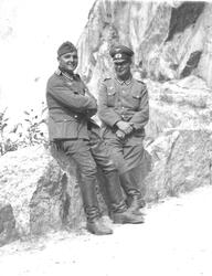 To tyske soldater tar seg en pause mens en kolonne militære 