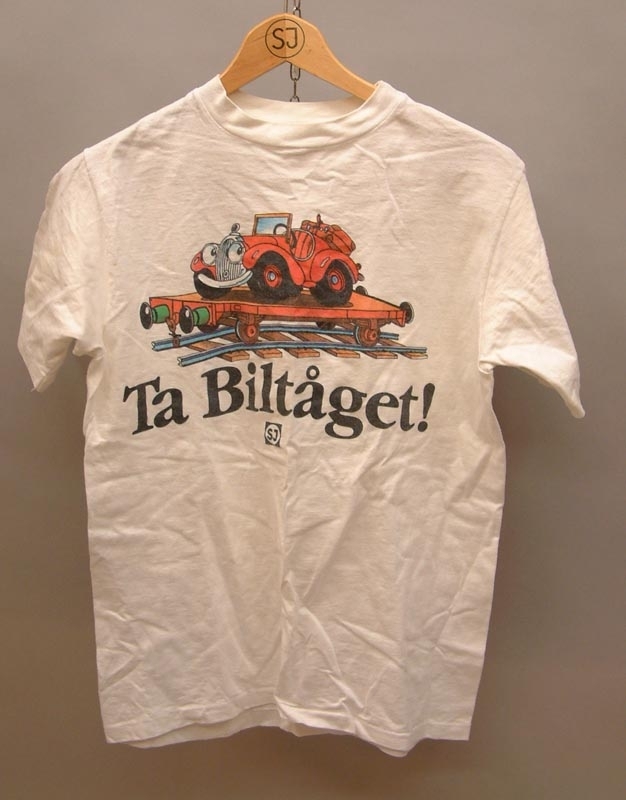 Vit t-shirt med texten "Ta Biltåget" och en illustration av en röd bil på en järnvägsvagn med räls och slipers
SJ-logga i blått, affärsområde Nord i svart text.

Storlek M 38-40.

Modell/Fabrikat/typ: Hanes Beefy