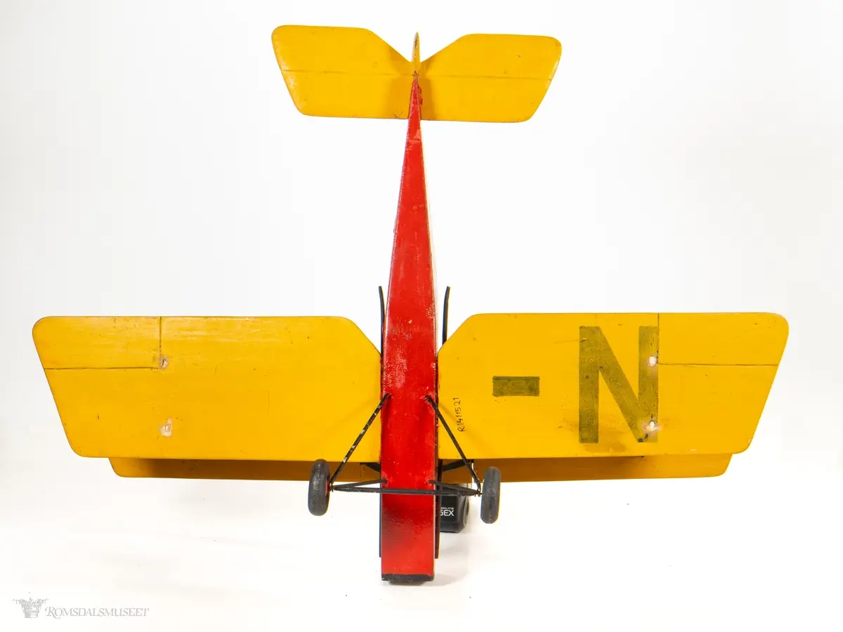Lekefly bygget i tre. Gjengir en propelldrevet dobbeltdekker. Kropp i massivt tre, hjuloppheng i metall med tre hjul. Vinger og halefinne utførte i tynne treplater.