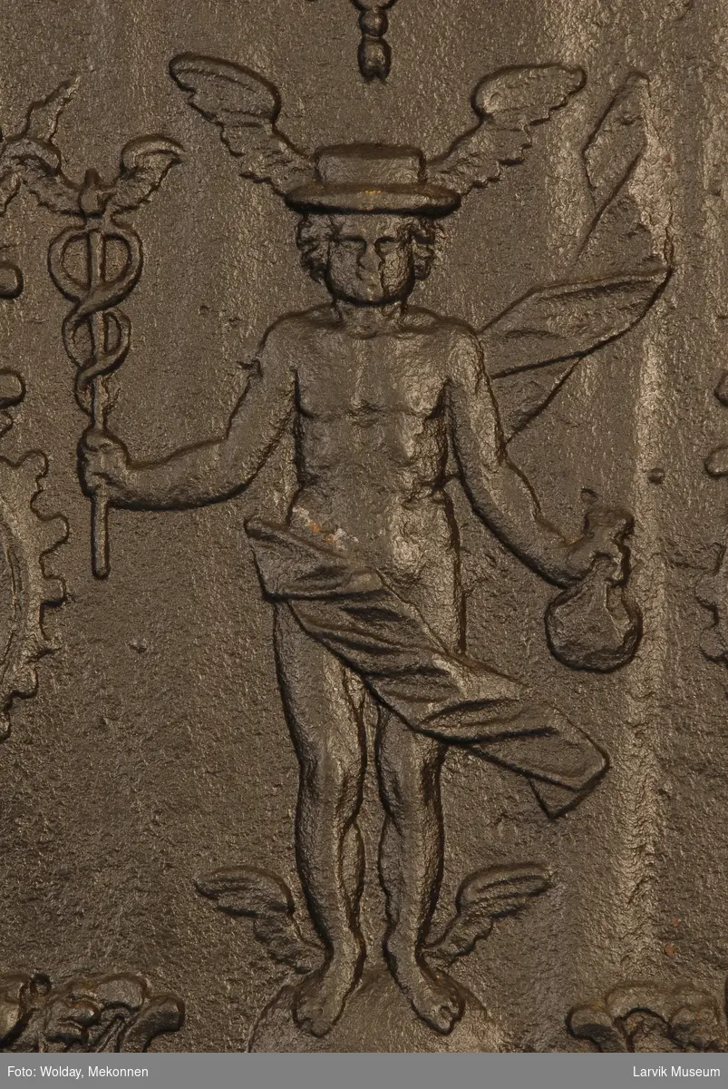 Merkur med vinget stav og pengepung stående  på kule, omgitt av symmetrisk rokokko-ornamentikk, hvori maske og fugler øverst og løver nederst...