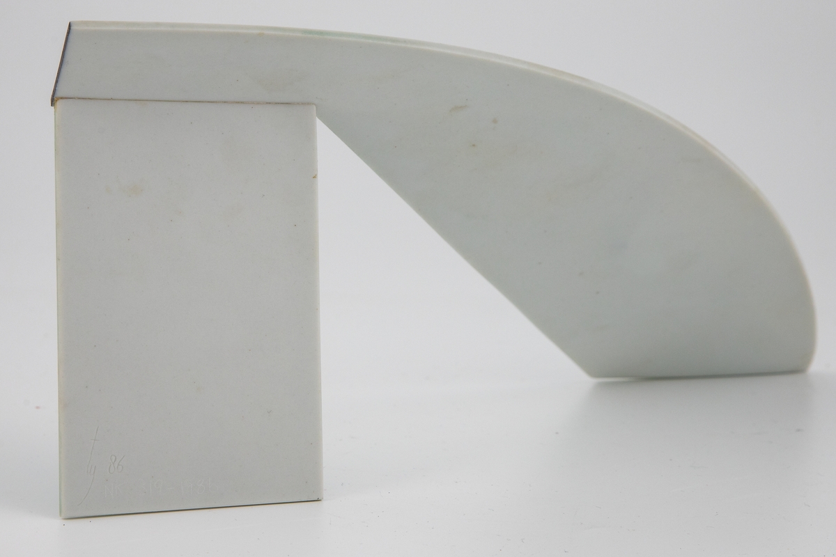 Keramisk objekt i tynn porselen, med en fremtoning som er på samme tid skjør og arkitektonisk. Abstrakt form av ett stykke, men optisk bestående av geometriske elementer som rektangel, parallellogram og bue. Den ene delen er brettet forover som en støtte; skråstilt for å oppnå en balanse som gjør at den tynne porselensskiven står med minimal berøringsflate to steder. Det åpne mellomrommet som oppstår oppfattes som en aktiv del av skulpturens form. De to stående delene har en lysgrønn emaljeglasur med ujevn tekstur, mens den buede overbygningen er hvit. Svarte smale streker i overgangen mellom den ene stående delen og buen, samt som en fri linje på den korteste stående delen.