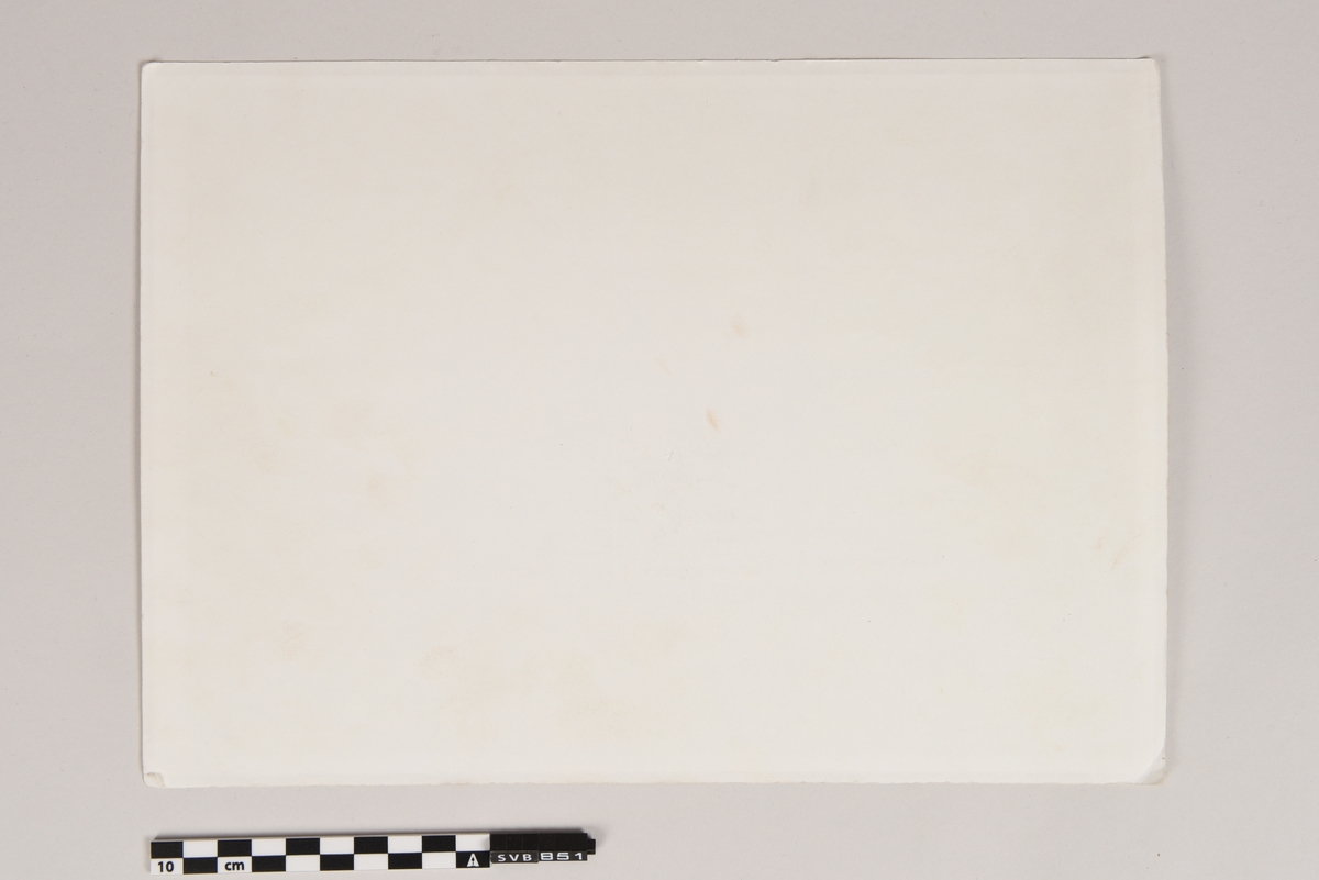 Dokument med trykt tekst og grafikk på svart bakgrunn. Arket er montert mellom to kunststoffolier, hvorav den ene øverste er transparent.