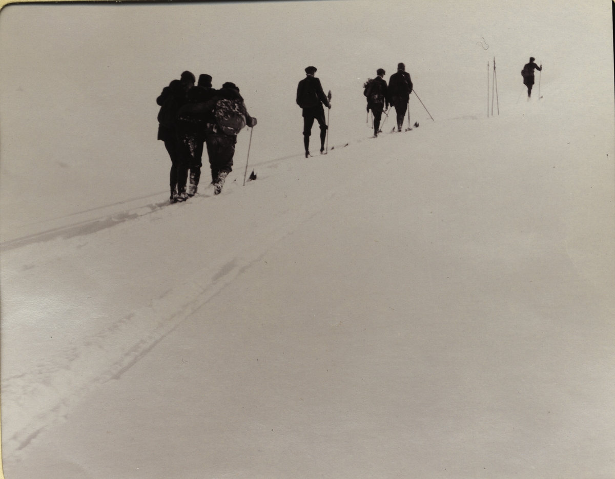 En skiløper, O. Bronn(?), har brukket beinet og blir støttet av løytnant Gelinet og Gerhard Kallevig. Fotografert i Jotunheimen i mars 1908.