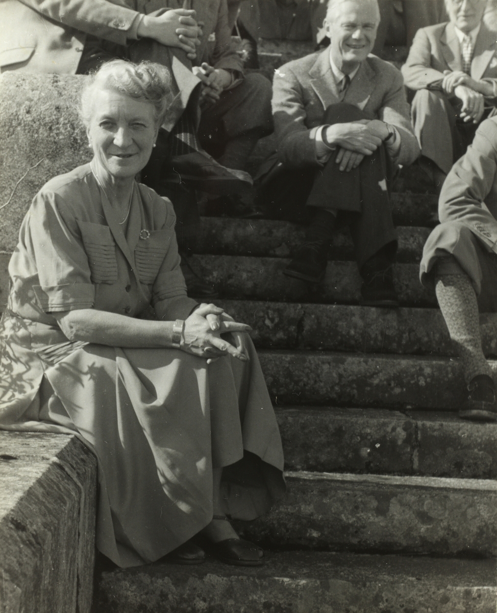 Antagelig Ingrid Kiær, vertinne for medlemmer av skiklubben Fram på besøk hos henne og hennes mann, direktør for Orkla Thorry Kiær. Her på trappen opp til Fjeldheim gård ved Prestbuvatnet i Meldal. Fotografert 1952.