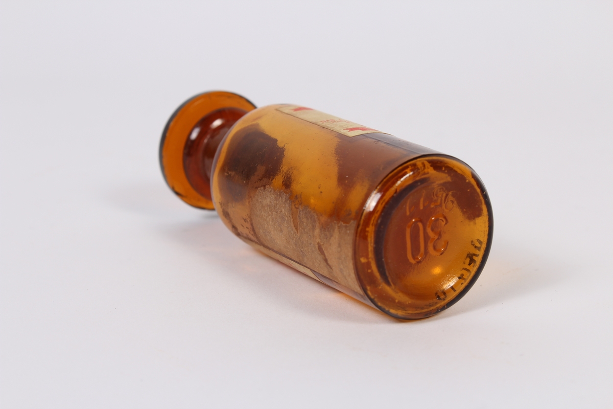 Liten brun glassflaske med kork og etiketter. Har inneholdt bedøvelsesmiddel. 
Gjenstanden har vore brukt i samband med dyrlegearbeid på Jæren.
