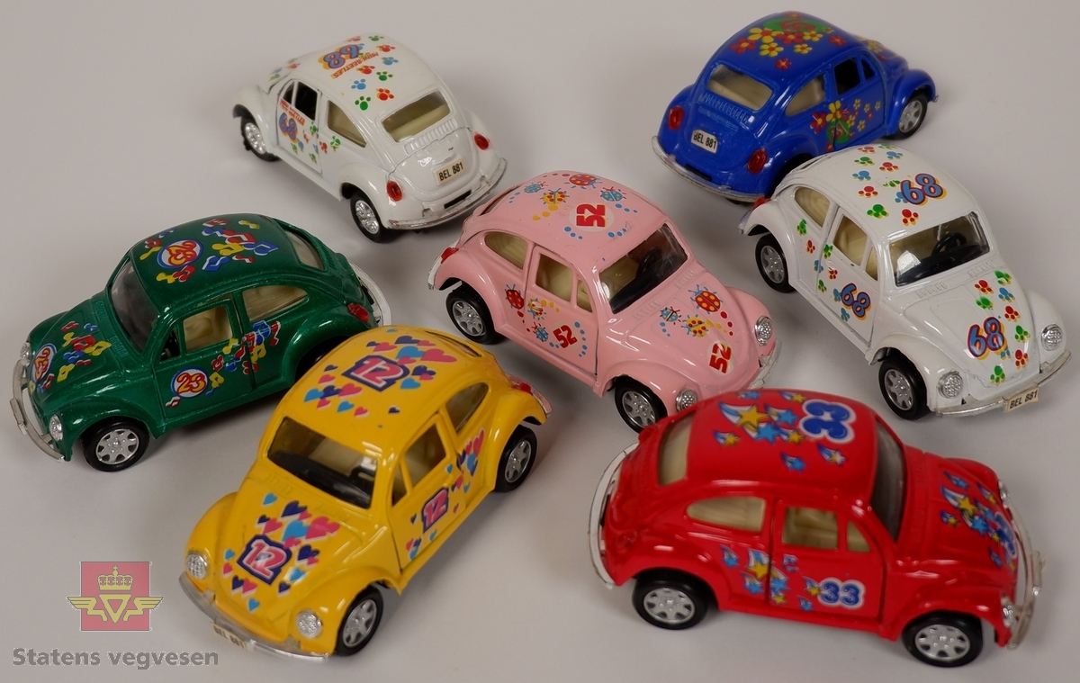 Miniatyrmodeller av Volkswagen Type 1. Syv biler med hovedfargene gul, hvit, rød, grønn, blå og rosa. Bilene er laget hovedsakelig i metall med plastunderstell og detaljer.