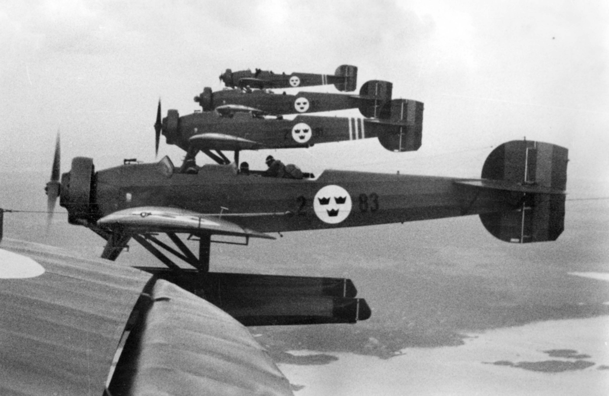 Flygbild av fem flygplan S 5, Heinkel He 5 Hansa i formationsflygning. Vy från sidan. 1930-tal.