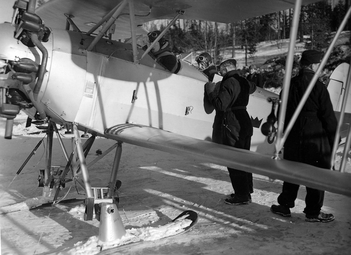 Förberedelse inför flygning av flygplan Sk 10, vintertid. Två flygare på plats i flygplanet och mekaniker i arbete. Cirka 1932-1939.