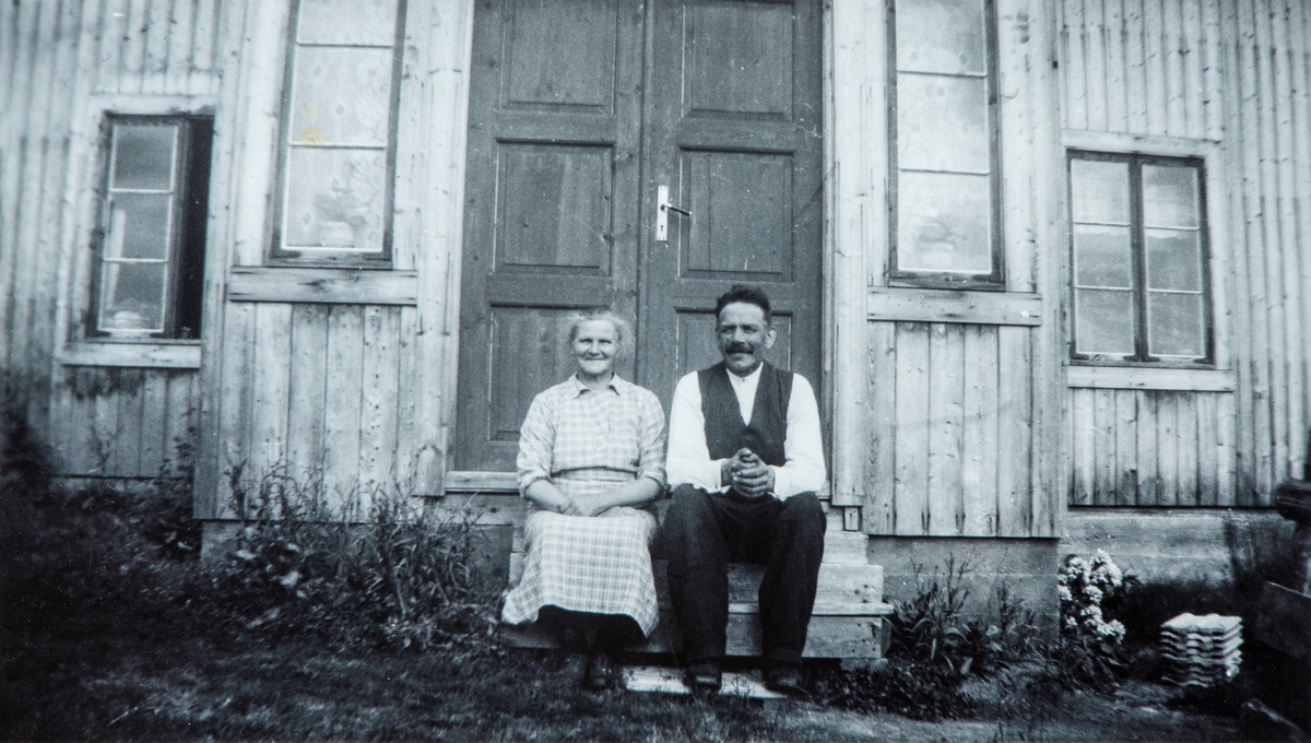 Nille (Syversdatter, f. 1889) og Markus Pedersen (f. 1885) (gift 12.09.1908) på trappa i Nybakk, Vallset, som de forpaktet fra 1922. Tidspunkt for fotografering, muligens i 1930-årene da de gikk over fra å forpakte eiendommen til å eie den.