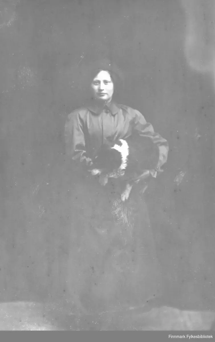 Fotoatelierportrett av en ukjent kvinne som holder en hund i armene sine.