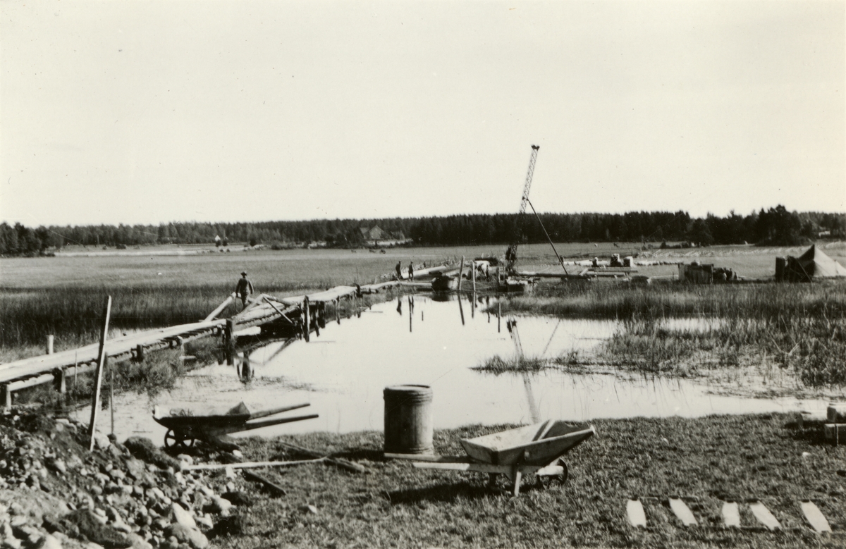 Text i fotoalbum: "Brobyggnad i Storvreta under mötet 1931. Vi började med att reda pålkran och slogo ned långa pålar i närheten av spången".